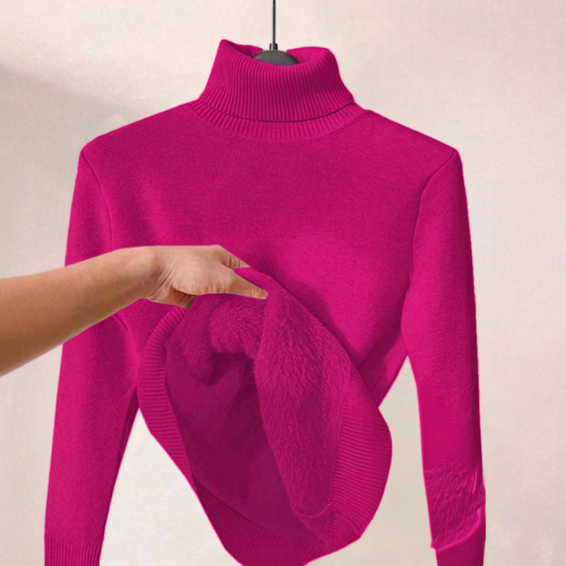 A bright fuchsia pink turtleneck sweater displayed on a hanger against a light beige wall, with a hand holding up the fuzzy ribbed inner lining to show its texture.