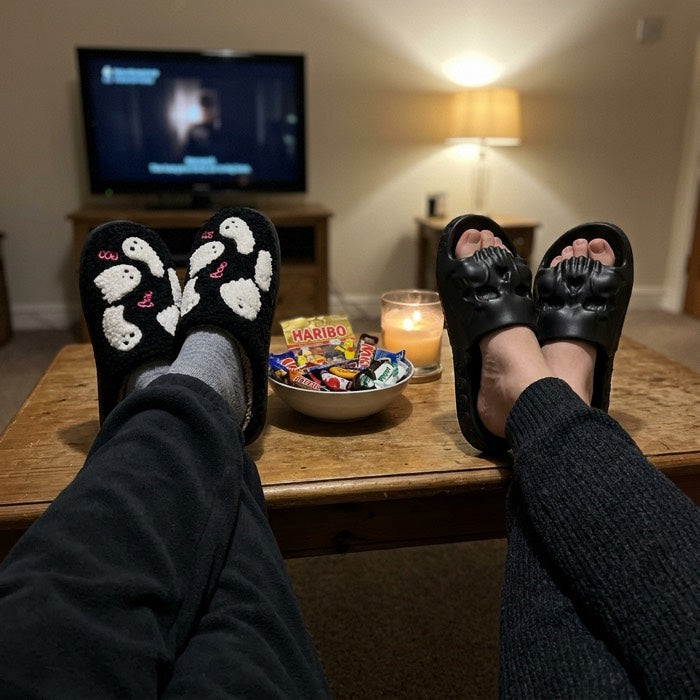 Two pairs of Halloween slippers on a coffee table