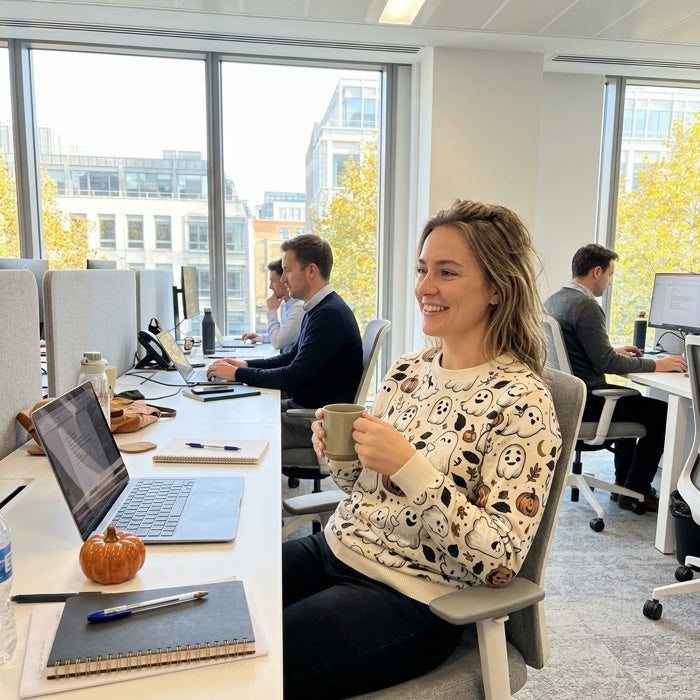 Woman in a ghost and pumpkin jumper at her desk